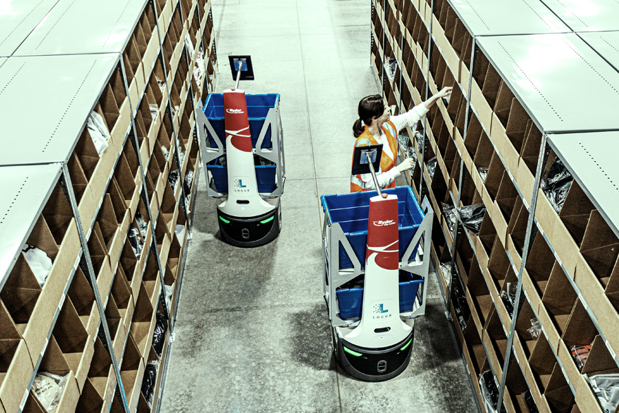 A Ryder warehouse employee working alongside automated technology to sort packages